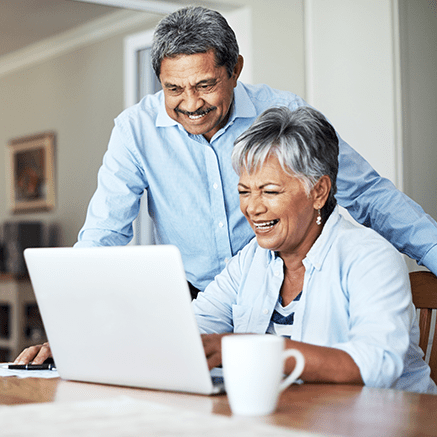 couple smiling looking at laptop